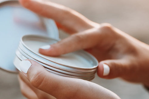 holding a tin of sunscreen