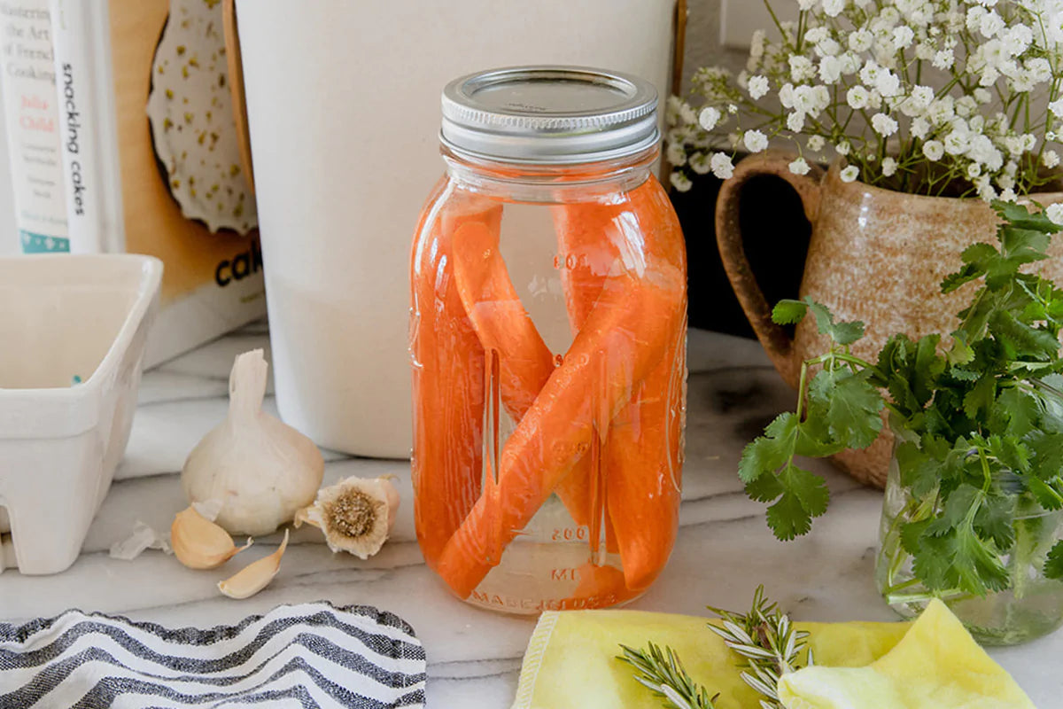 a glass jar full of water and carrot sticks