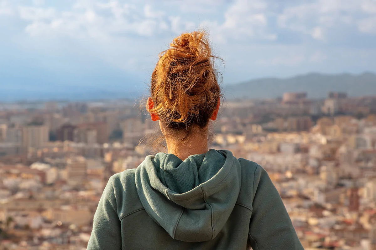 woman with red hair looking out onto a cityscape
