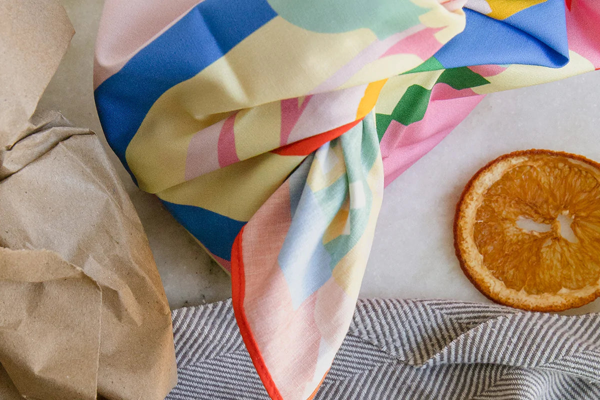 eco-friendly gift wrap ideas, including kraft paper, colorful printed scar, and dried orange slice