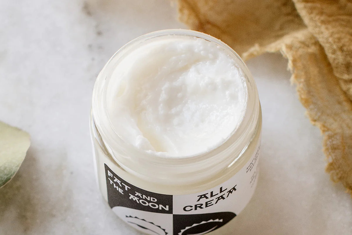 An open jar of white moisturizer cream from Fat and the Moon