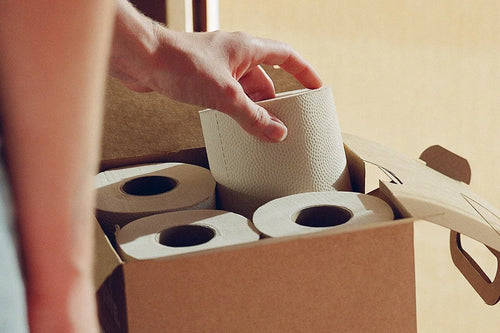 Reaching for a roll of toilet paper in a cardboard box