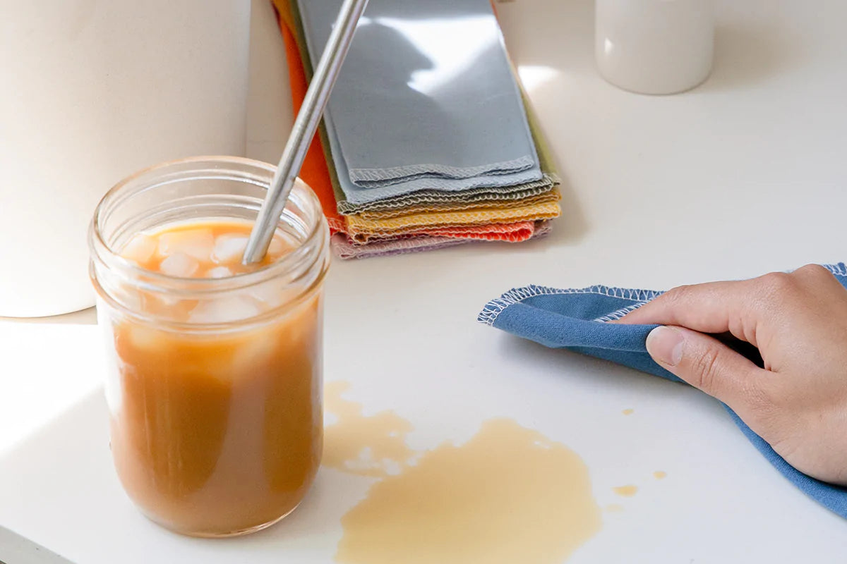 cleaning up spill from a glass jar of iced coffee with a reusable paper towel