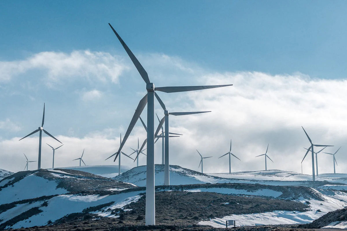 snowy hills dotted with tall white wind turbines