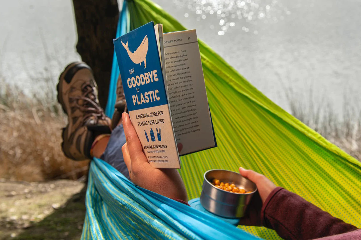 Person in a hammock holding a book titled 